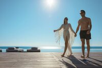 Couple walking hand in hand on a dock at sunset, embodying romantic getaways and serene retreats.
