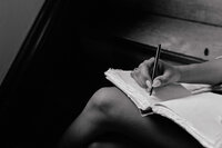 A black and white image of a website copywriter taking notes in her notebook