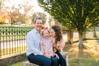 Mom and dad sit with daughter on bench in Tennessee park at golden hour