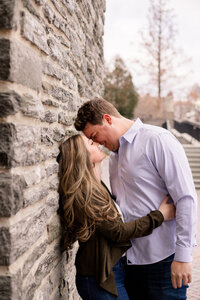 Couple kissing against a stone wall
