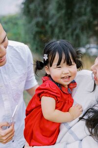 Toddler girl laughing with her parents during a Bay Area candid family session