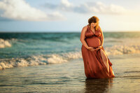 Pregnant mother holding her belly in the ocean during a beach maternity session in Atlantic Beach North Carolina