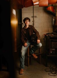 High school senior in welding gear posing in his welding teacher’s workshop near Mobile Regional Airport in Mobile, Alabama.