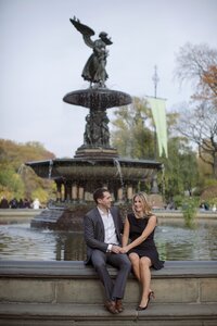 Central park engagement photos, Deborah Zoe Photography. A couple laugh together as they sit on the Bethesda Fountain in Central Park.
