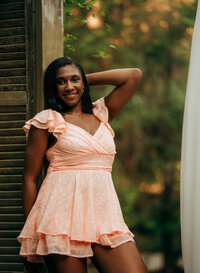 Senior portrait at Bella Sera Gardens in Loxley, Alabama — leaning against vintage shutters in a
pink dress.