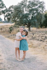 sisters wearing dresses and bows in their hair and hugging