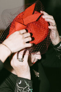 Sophisticated moment of the mother of the bride putting on a luxury hat, highlighting elegant wedding fashion and preparations.