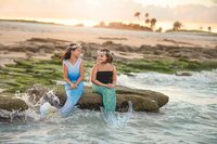 Mermaid-inspired image of two girls laughing together on a coastal rock while ocean waves splash at sunset in Palm Coast during a Mermaid Imagination Session. (Photographed by Nature's Child Photography)