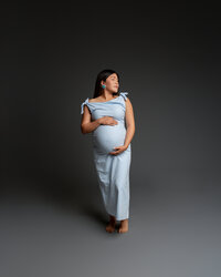 Pregnant woman in a soft blue dress posing gracefully, highlighting her baby bump during a maternity session with Kaitlyn Dawn Photography in Yucaipa.