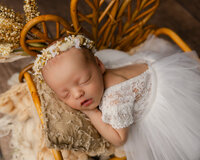 Newborn baby swaddled in pink with a delicate floral headband. Photographed by Inland Empire newborn photographer Kaitlyn Dawn Photography.