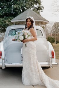 Bride posing with bouquet and vintage car at Stonehedge Venue in Buford.