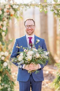 Groom holding ivory and blue bridal bouquet with winter greenery by Flowergirl Cville, Charlottesville area florist | Photo by Xiaoqi Li Photography