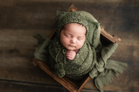 Baby boy wrapped in green during his newborn photography session in Southern Minnesota.