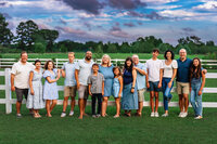 Large extended family standing together by white fence at a farm during sunset in New Bern North Carolina