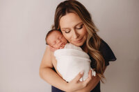 Newborn Photographer in Charleston - Mother embraces her infant during Newborn Portrait Session in Charleston, SC.
