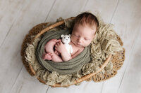 Newborn boy wrapped in sage green during his newborn session in Southern Minnesota.