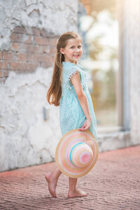 Young girl walking outdoors wearing wide brim hat in natural light in Eastern North Carolina