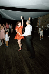 Joyful moment of the bride's parents dancing at the wedding reception, captured with a stylish direct flash.