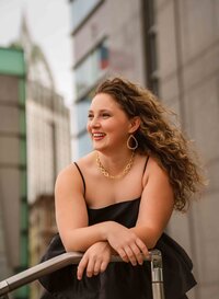 Senior girl in black dress posing near the RSA tower in downtown Mobile, Alabama.