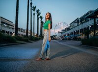 Senior portrait at The Wharf in Orange Beach, Alabama — standing in a small street with the
Ferris wheel glowing behind her.