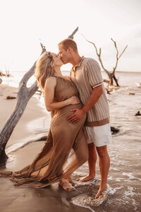Folly Beach Maternity Photographer -- Pregnant woman poses for Maternity Photos at the Lighthouse Inlet Heritage Preserve on Folly Beach with iconic views of the Morris Island Lighthouse in the distance.