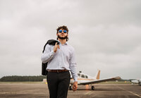 Senior portrait at a small hangar near Mobile International Airport in Mobile, Alabama — suit
jacket over his shoulder looking off in the distance.