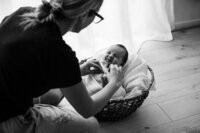 aimee kelly adjusting a baby blanket on a newborn during a newborn baby photoshoot in aimees new plymouth portrait studio