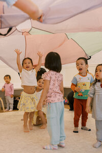 Toddlers having fun under a parachute at The Bunny Hive Mountain View