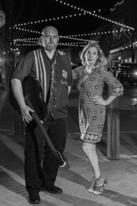 Two people posing together while one holds a guitar