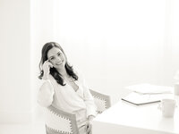Black and white photo of a DFW small business woman sitting at her desk smiling.