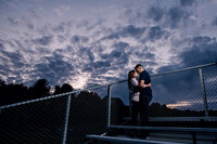 high school sweethearts engagement photos at former high school football field at night