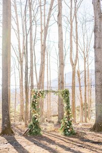 Winter woodland ceremony arbor with fresh greenery and ivory florals by Flowergirl Cville, Charlottesville florist, at Indigo House in Afton, VA | Photo by Xiaoqi Li Photography