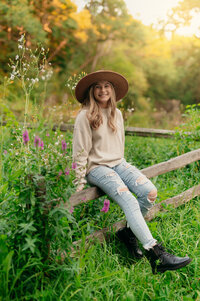 A girl from Kettle Moraine High School perches on a split rail fence in Eagle's Paradise Springs while having her senior photos taken.