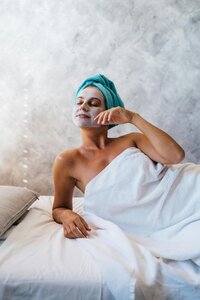 Woman enjoying self-care with a face mask and towel wrap, embracing relaxation and wellness travel.