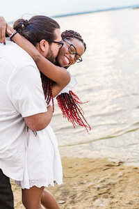 Playful interaction between engaged couple giving kisses during a portrait session at Murrell Park in Dallas-Fort Worth.