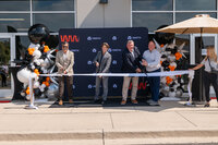 A group of people with large scissors cutting a ribbon