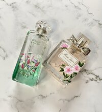 hermes and dior perfume bottles adorned with hand painted florals on marble background