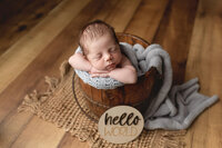 Newborn boy posed safely in a wooden bucket during his Newborn Photography session near Mankato, Minnesota.