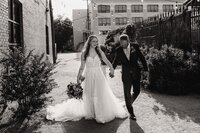 a bride and groom walk hand in hand in an ally at their abilene texas wedding