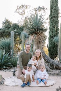 family of 5 sitting and smiling at arizona cactus garden