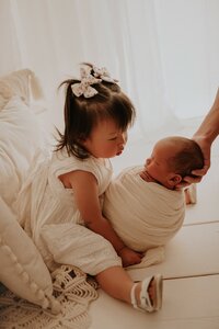 Older sibling under 3 cuddling newborn during studio portrait session