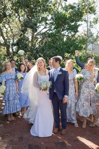 Bride and Groom celebrate as wedding party cheer behind them.
