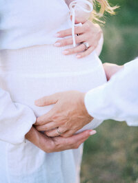 Close-up of a pregnancy bump with hands over it