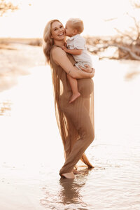 Folly Beach Maternity Photographer -- Pregnant woman poses for Maternity Photos at the Lighthouse Inlet Heritage Preserve on Folly Beach with iconic views of the Morris Island Lighthouse in the distance.
