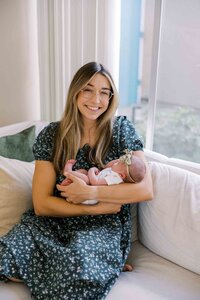 New mom smiling with joy as she cradles her newborn baby girl during her Palo Alto newborn photography session