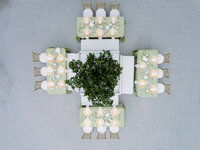A precise top-down view of reception tables featuring sage linens and gold accents, highlighting the refined composition of a multi-day wedding celebration.