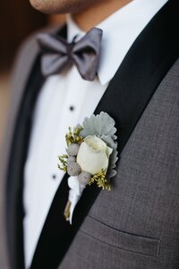 Detail photo of groom in grey tux with neutral soft Boutonniere