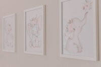 Framed cartoon elephants hang on a nursery wall.
