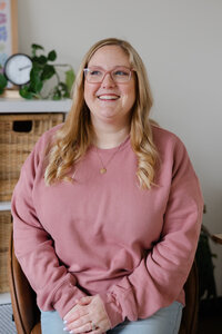 Woman with blonde hair in pink sweater smiling while seated in studio. Photograph by Yucaipa branding photographer Kaitlyn Dawn Photography.