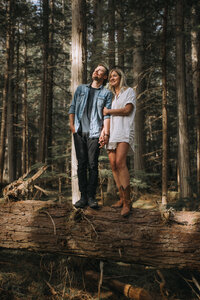 Couple standing on a log in the old growth forest of Mt.Robson provincial park.